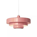 A pink Clérachic tiered pendant on a white cord against a white backdrop, with three glossy tiers and a lit underside.