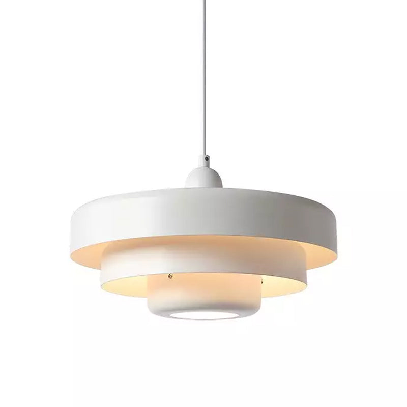 A white Clérachic tiered pendant on a white cord against a white backdrop, with three tiers and a glowing underside.