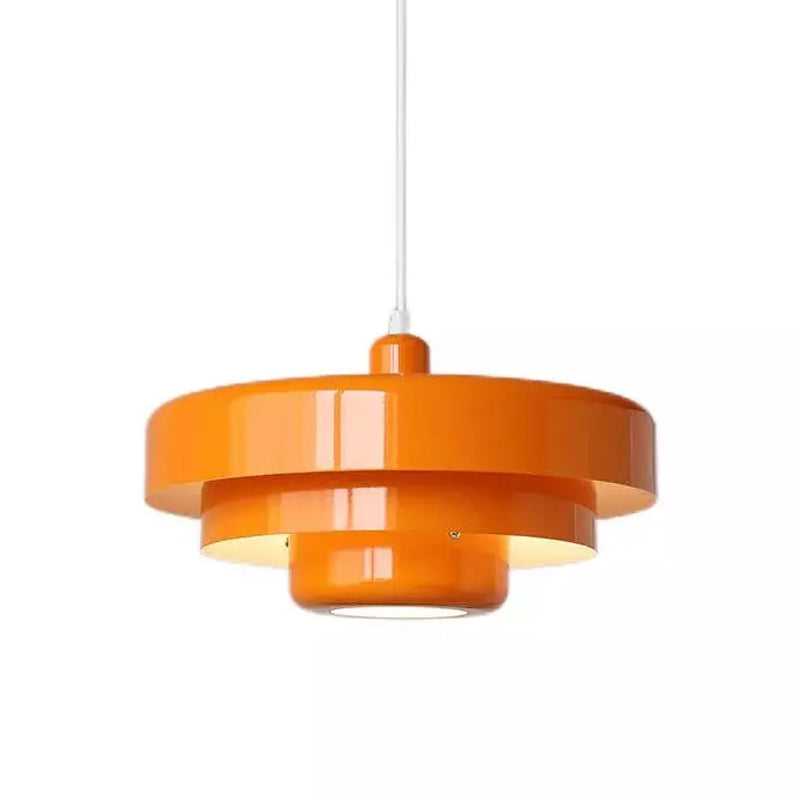 An orange Clérachic tiered pendant on a white cord against a white backdrop, with glossy tiers and a lit underside.
