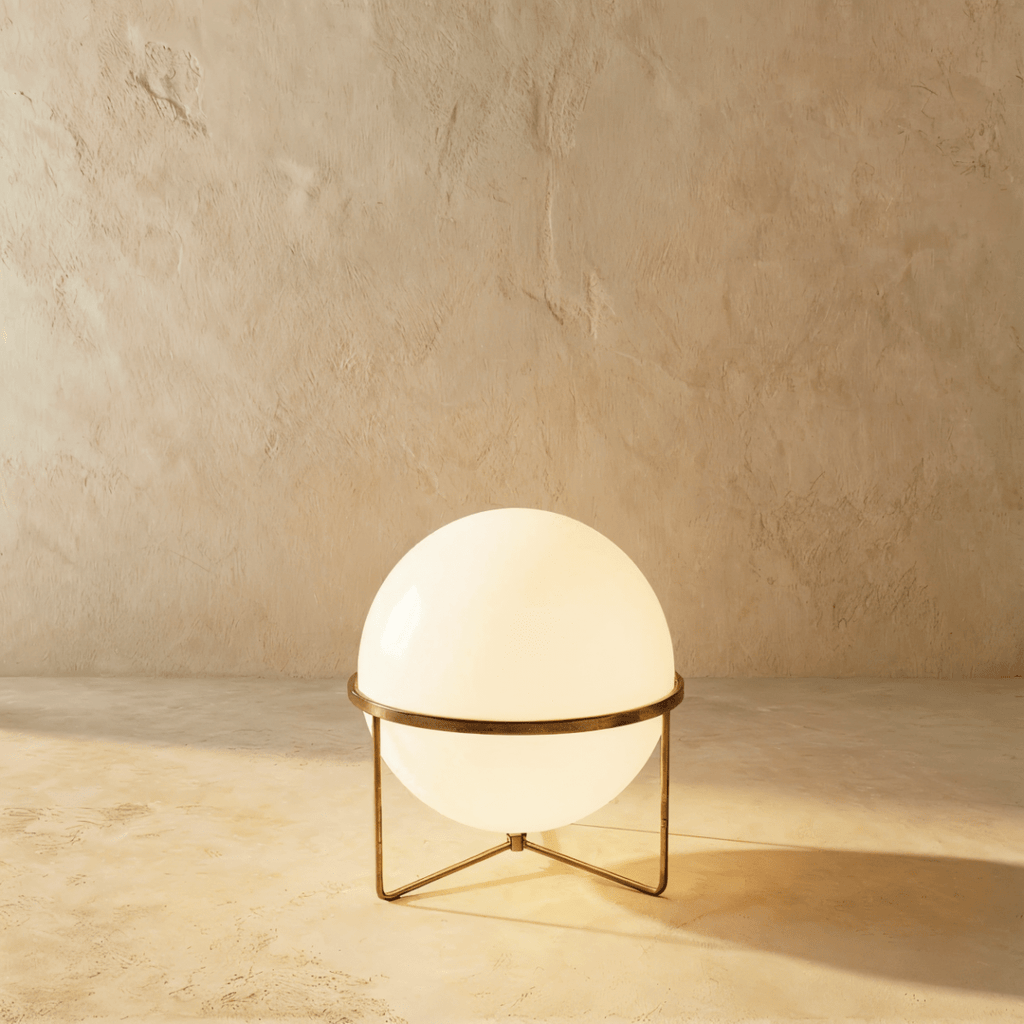 Clérachic single-globe sphere lamp in vintage brass, lit, the aged metal band reading darker than the polished versions.