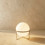 Clérachic single-globe sphere lamp in vintage brass, lit, the aged metal band reading darker than the polished versions.