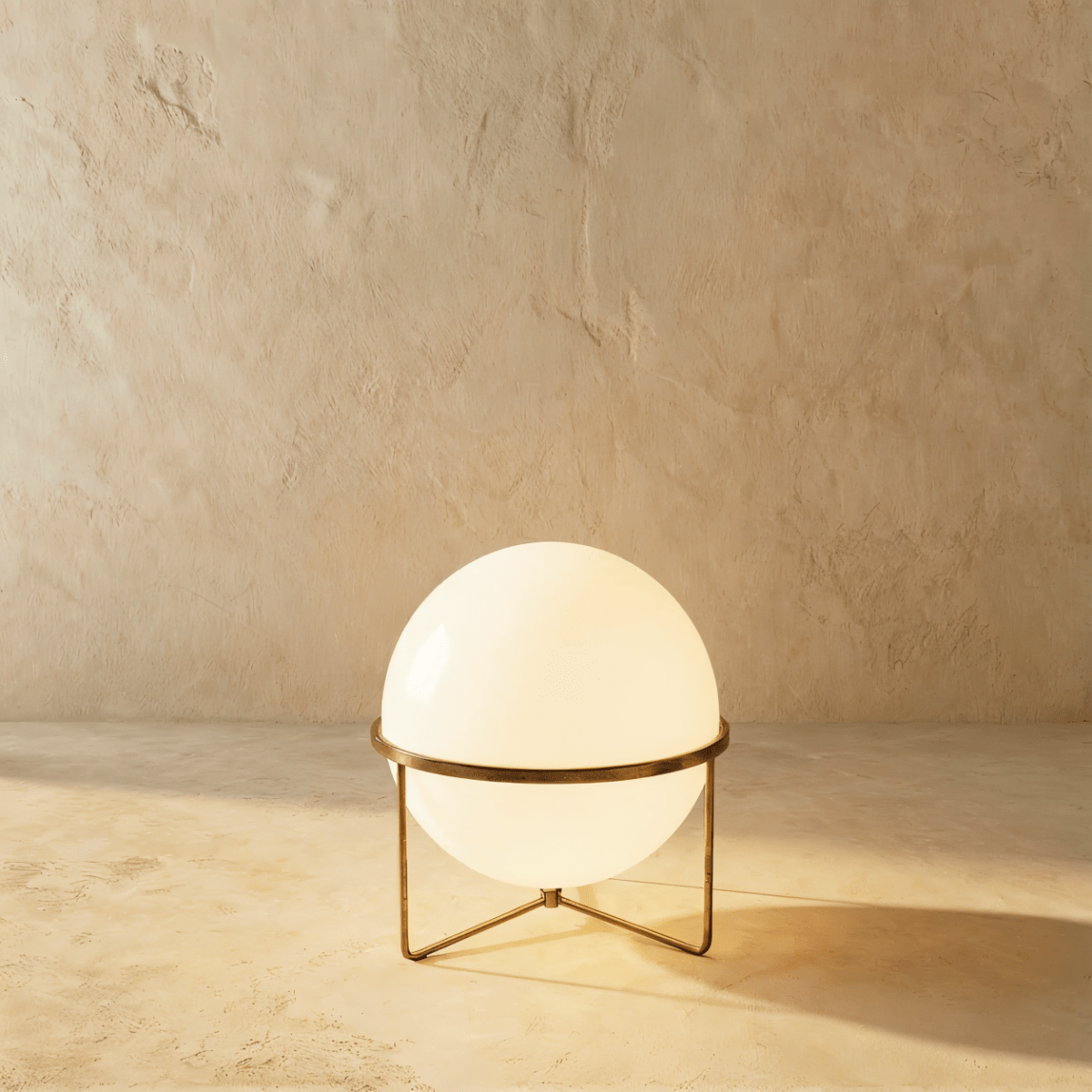 Clérachic single-globe sphere lamp in vintage brass, lit, the aged metal band reading darker than the polished versions.