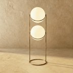 Clérachic two-globe sphere lamp in vintage brass on the taller column, lit, the band sitting high on the lower globe.