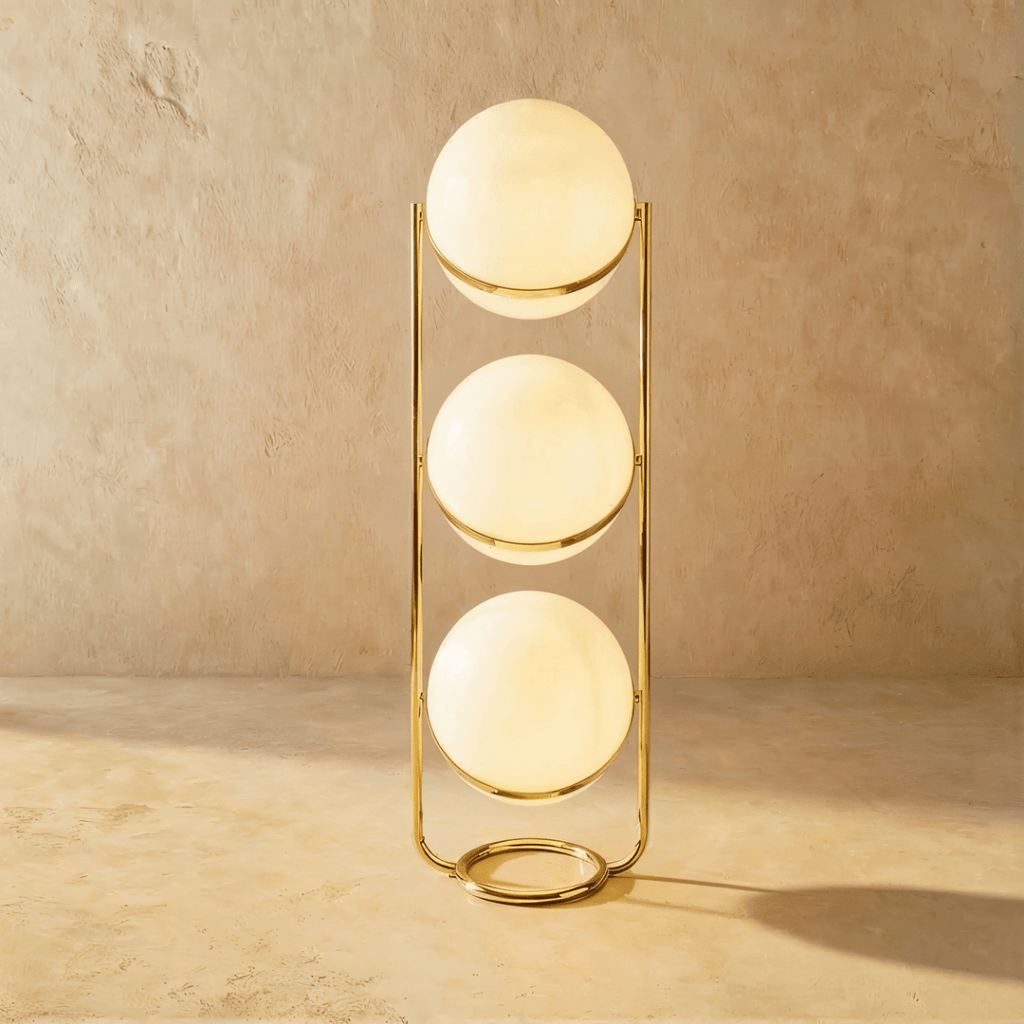Clérachic three-globe sphere lamp in polished brass, all three globes lit above a ring base narrower than the globes themselves.