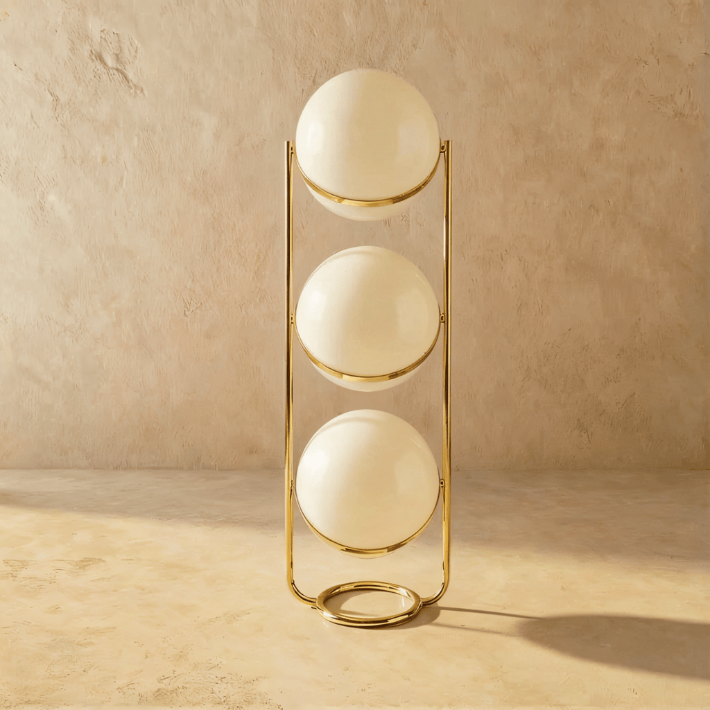 Clérachic three-globe sphere lamp in polished brass, shown unlit, each white globe shaded and marked by a specular highlight.