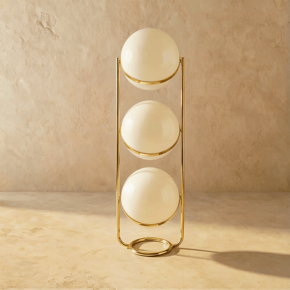 Clérachic three-globe sphere lamp in polished brass, shown unlit, each white globe shaded and marked by a specular highlight.