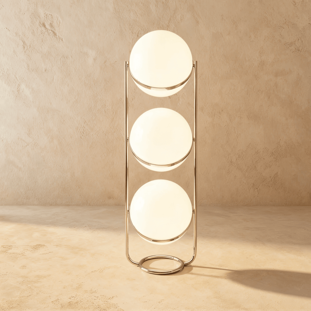 Clérachic three-globe sphere lamp in silver, all three globes lit on the tall frame against studio plaster.