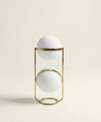 Clérachic two-globe sphere lamp in brass, unlit on a plain cream ground, the upper band mid-way up its globe and the lower band near the top of its own.