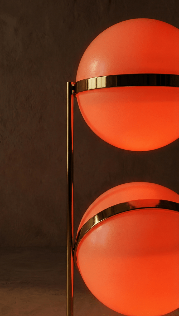 Clérachic two-globe sphere lamp in brass, a close crop of two orange-lit globes with the lower band tilted off-horizontal.