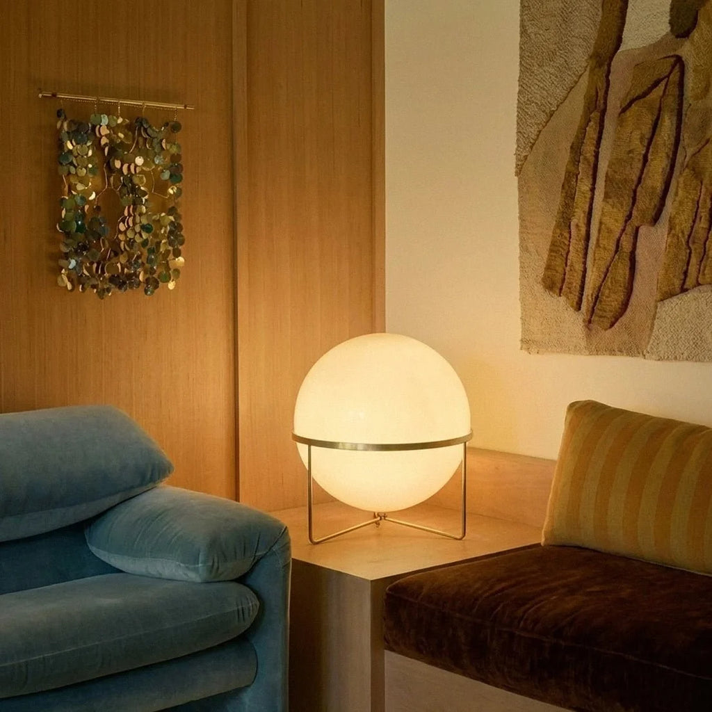 Clérachic single-globe sphere lamp lit on the plinth, close enough to show the collar under the globe and the disc wall hanging behind.