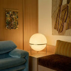 Clérachic single-globe sphere lamp lit on the plinth, close enough to show the collar under the globe and the disc wall hanging behind.