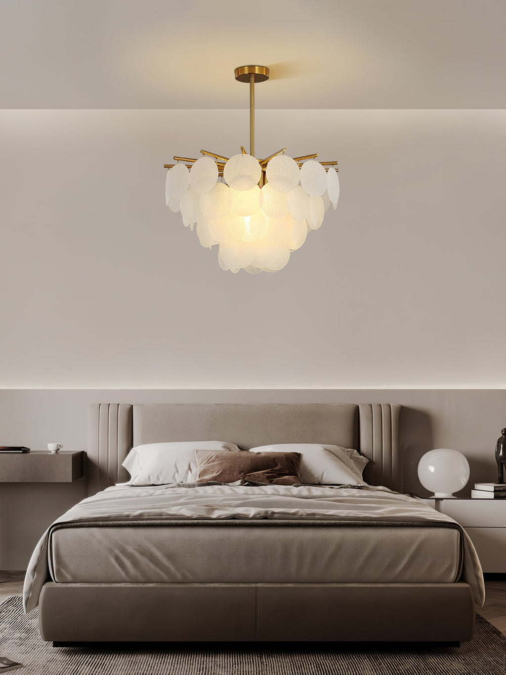 Compact Clérachic chandelier of layered glass discs, hung in a calm taupe bedroom above a bed with soft grey bedding.