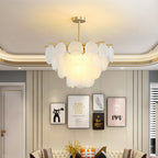 Frosted glass discs on a gold-toned frame, this Clérachic chandelier lit beneath a curved ceiling with framed prints behind.