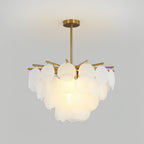 Close, lit view of the layered frosted discs and brass-toned arms of this Clérachic chandelier against a pale grey wall.