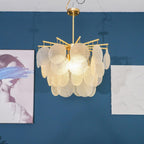 Lit Clérachic chandelier up close in front of a blue wall, with the textured glass discs showing a rippled surface.