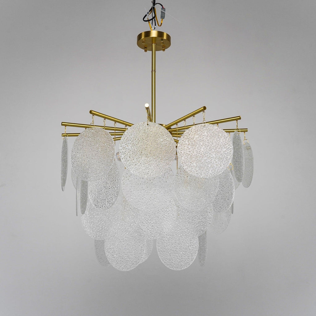 Unlit rippled glass discs and brass arms on this Clérachic chandelier, seen from slightly below against a soft grey backdrop.