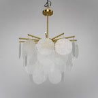 Unlit rippled glass discs and brass arms on this Clérachic chandelier, seen from slightly below against a soft grey backdrop.