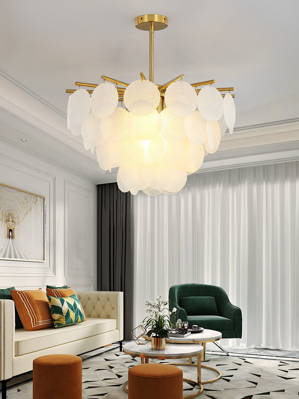 A Clérachic frosted disc chandelier lit above a living room with a cream sofa, a green armchair and a pale curtain.