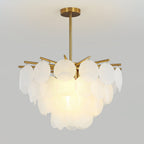 Clérachic chandelier lit warmly on a grey backdrop, with large frosted discs on brass-toned arms and a short brass rod.