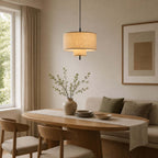 Lit Clérachic pendant over an oval wooden table set with a runner and plates, an olive-green cushioned bench against the wall.