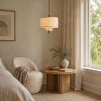 Clérachic linen pendant above a bedroom corner with a round boucle chair and a drum-shaped wooden side table.
