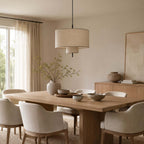 Clérachic linen pendant suspended above a long oak table with cream chairs, a vase of branches catching light from the window.