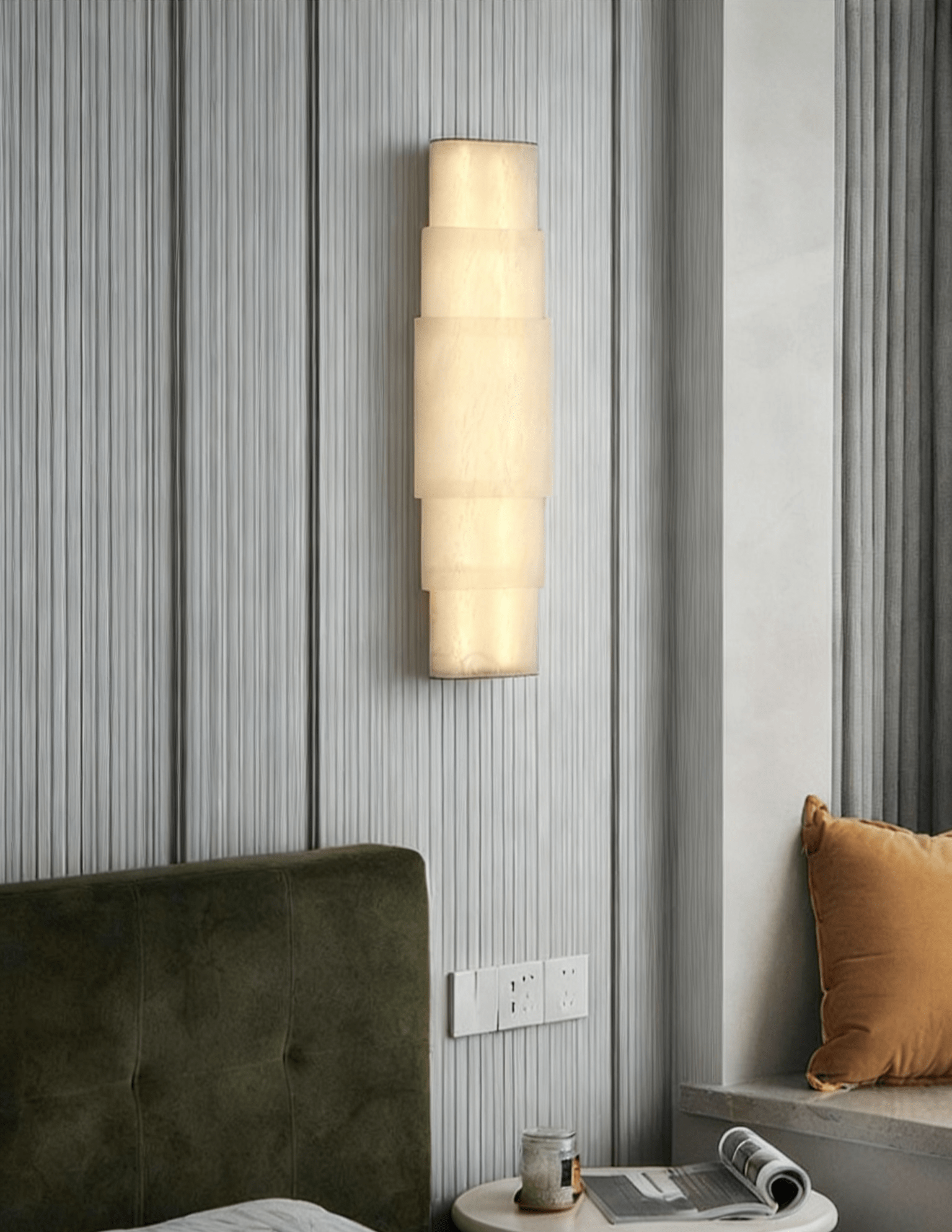 Clérachic tiered sconce on fluted white panelling above a green velvet bed and round side table.