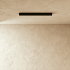Clérachic linear light head in black, seen at a slight angle with its face dark against the plaster.