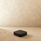Clérachic Zigbee gateway in black, a rounded square box with a single side button, on a plaster floor.