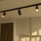 Clérachic spotlight heads in black, three along one rail above a kitchen with the outer two lit and the middle one dark.