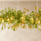 A close detail of the Clérachic chandelier's green glass leaves, lit from within along a brass branch.
