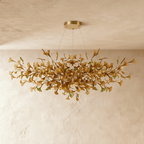 Clérachic's chandelier in its round form, glowing warm through a dense cluster of amber glass leaves.