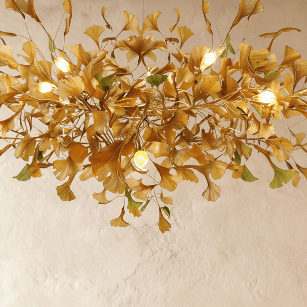 A close detail of the Clérachic chandelier's amber glass leaves, lit from within on slender brass stems.
