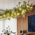 A closer view of the Clérachic chandelier's linear leaves, glowing warm beside a dining room's sheer curtain.