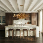 Clérachic's chandelier in its round form, amber glass leaves glowing above a marble kitchen island.