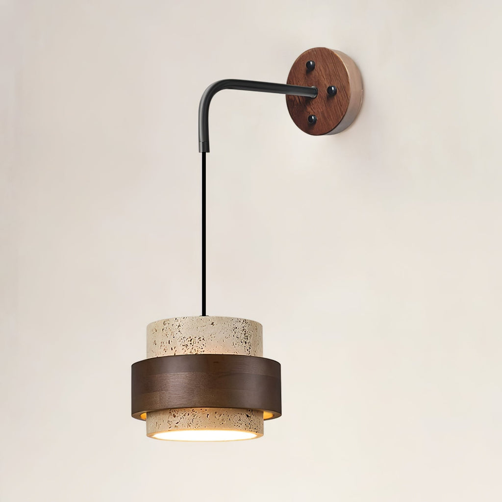 Front view of this Clérachic wall light, its black arm dropping from a walnut wall plate to a lit travertine and dark walnut shade.