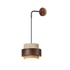Side view of this Clérachic wall light on a white backdrop, its black arm and walnut plate above a lit travertine and walnut shade.