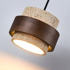 Tilted close view of the walnut ring wrapped around the travertine body of this Clérachic wall light, with its glowing base.