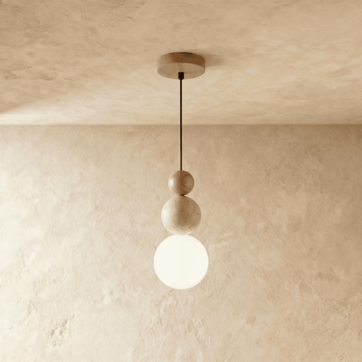 Clérachic stacked pendant with wood, speckled travertine and a lit opal white globe, on a black cord against a plaster wall.