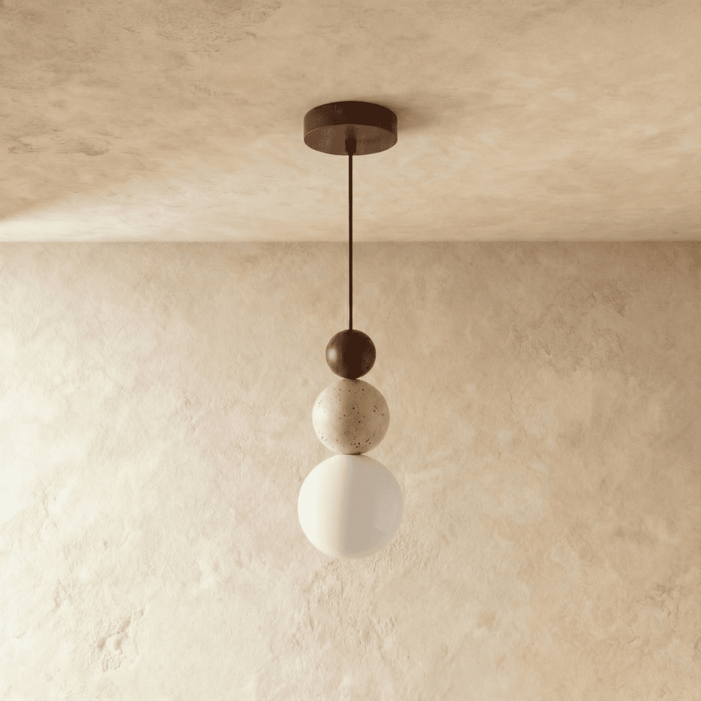 Clérachic walnut-toned stacked pendant with a travertine bead and a white glass globe, shown unlit against soft plaster.