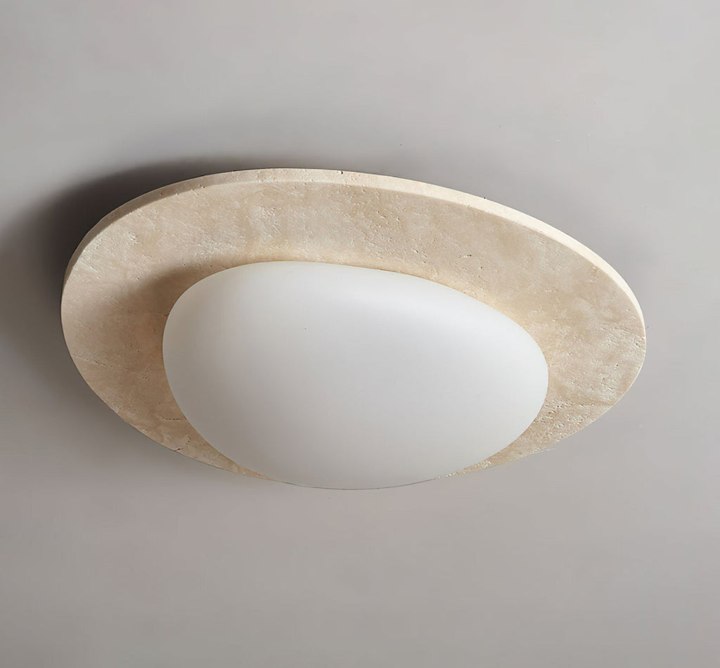 This Clérachic ceiling light switched off on a grey ceiling, with a creamy veined travertine rim and an opaque white glass shade.