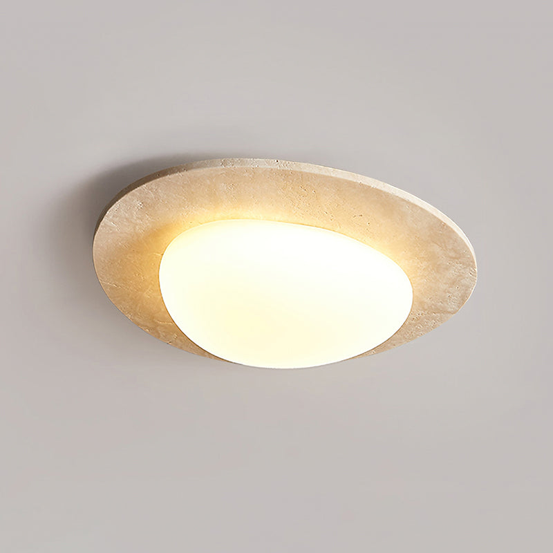 Larger-looking Clérachic ceiling light glowing against a grey ceiling, with a wide travertine rim around a rounded white shade.