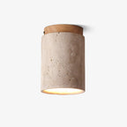 Clérachic ceiling light on a plain white backdrop, a travertine cylinder with a pale wood cap and a warm glow at its open base.