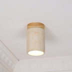 This Clérachic ceiling light in pale yellow travertine with a wood cap, lit below a white cornice and panelled wall.