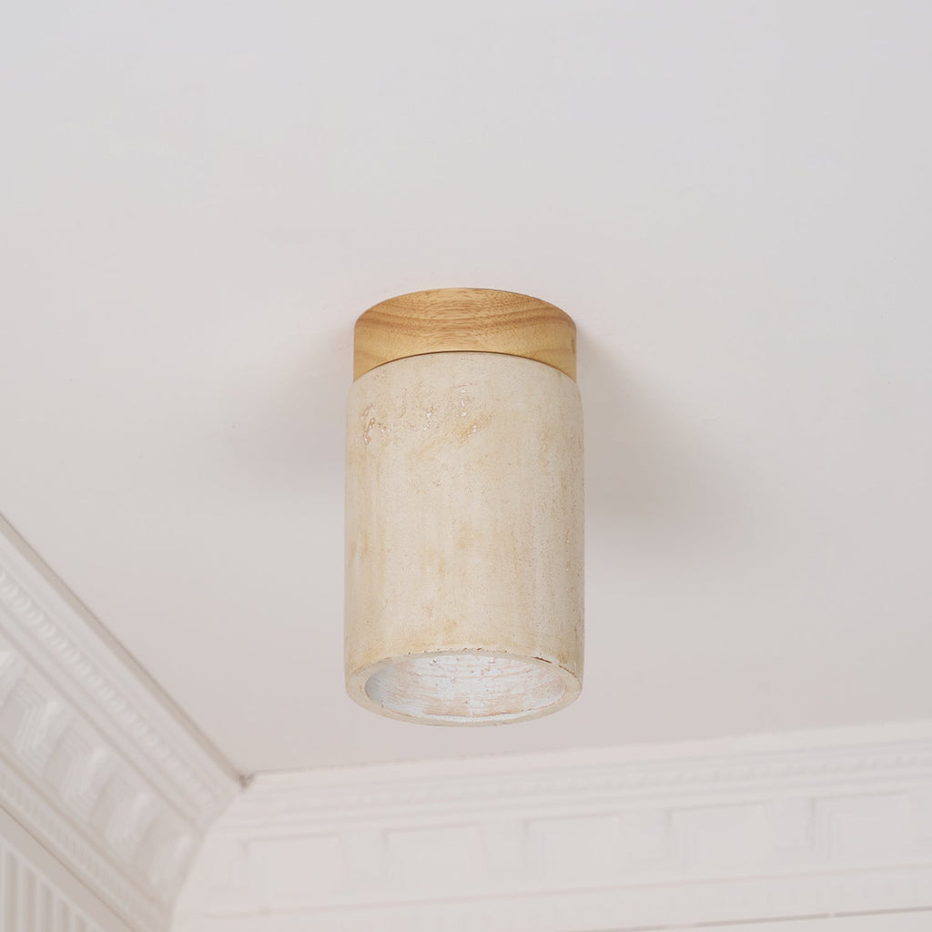 Clérachic travertine ceiling light switched off, the wood cap and stone shade clear against white cornice moulding.