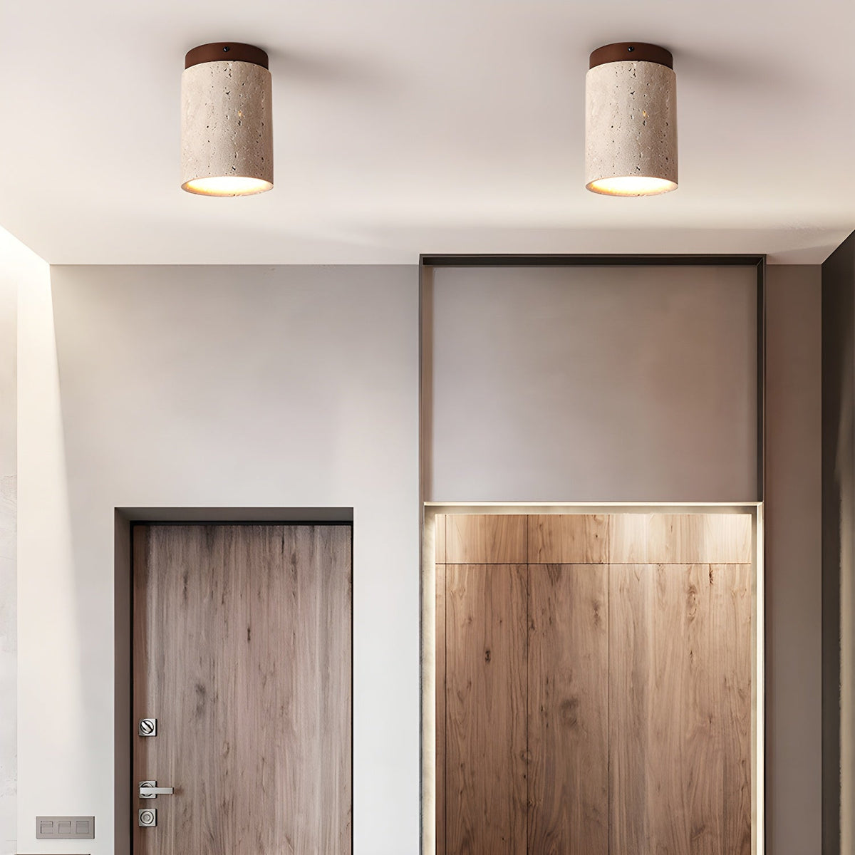 Two Clérachic travertine ceiling lights in a hallway with wood-veneer doors and cabinets, both glowing from their open bases.
