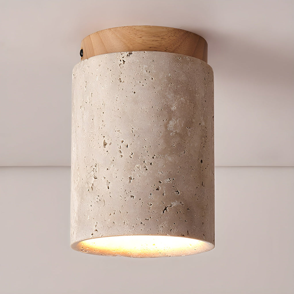 Clérachic ceiling light with a wood-colour cap, the porous travertine surface showing its natural pitting above a lit rim.