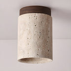 Walnut-capped Clérachic ceiling light viewed from below, with the thick stone rim and natural pores of the travertine visible.