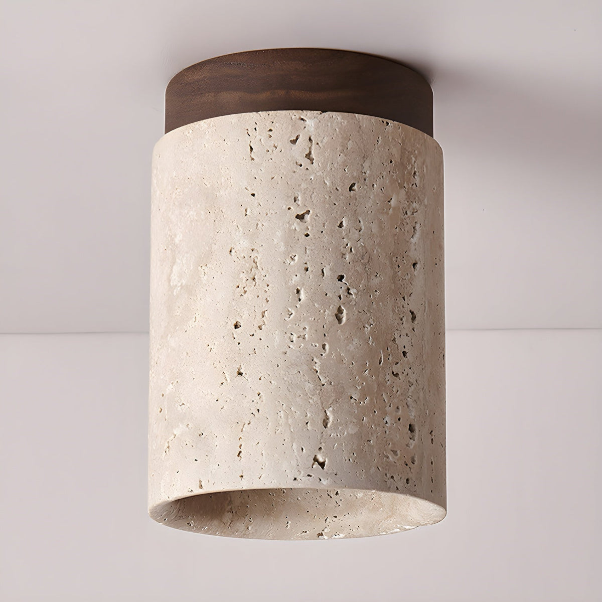 Walnut-capped Clérachic ceiling light viewed from below, with the thick stone rim and natural pores of the travertine visible.