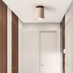 Walnut-cap Clérachic ceiling light lit above a narrow white hallway lined with dark wood panels.
